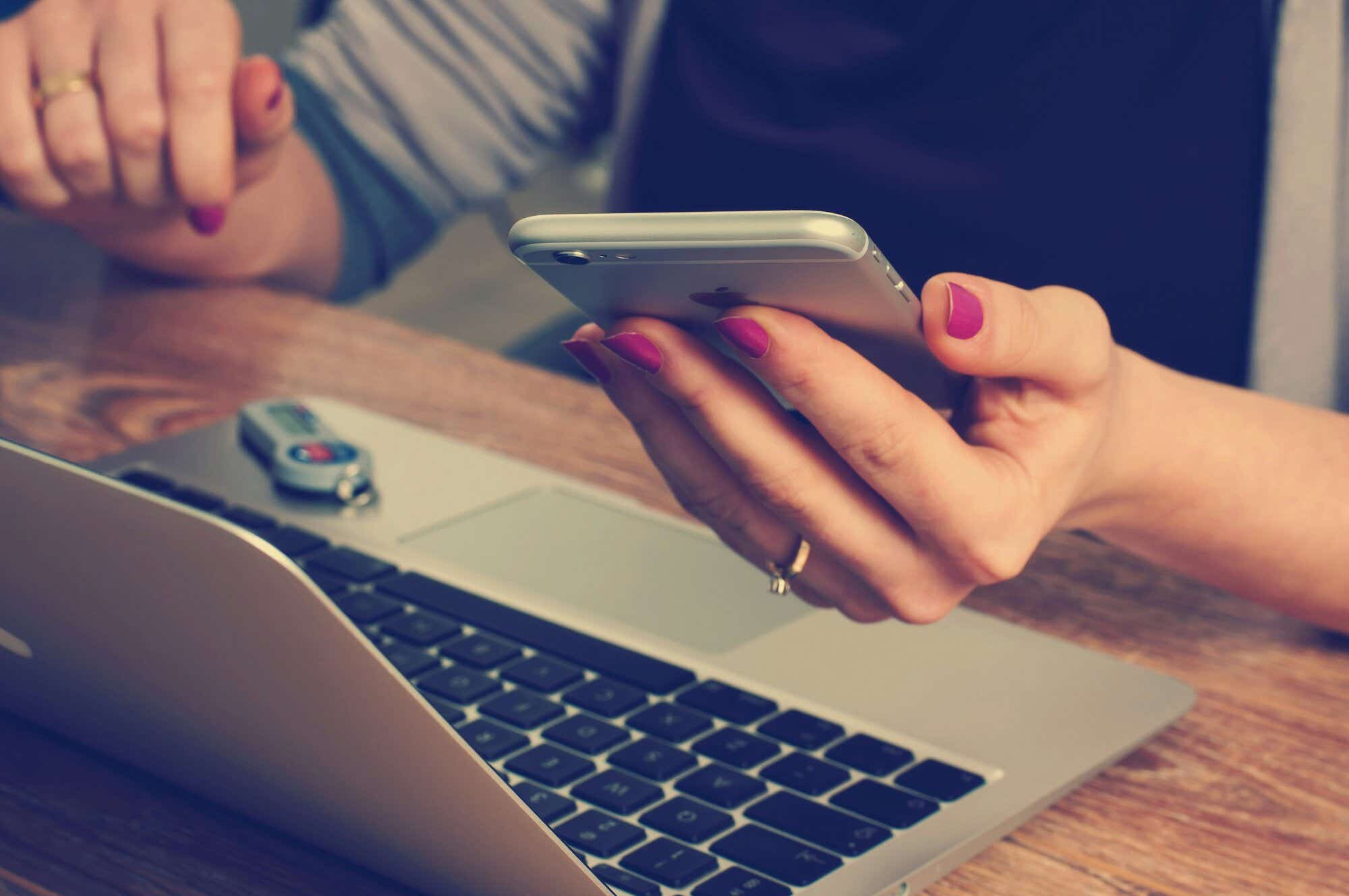 woman looking at her phone and laptop